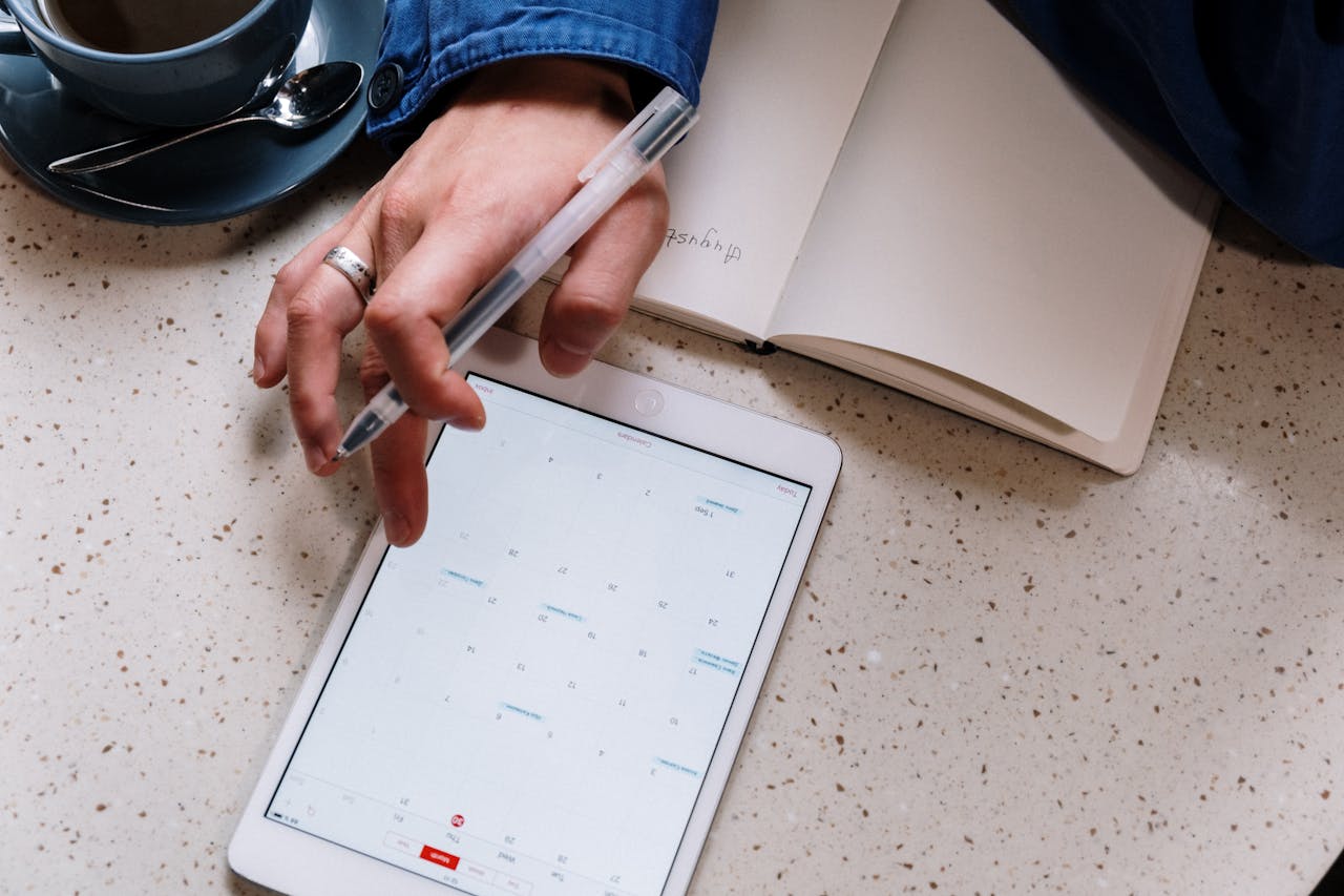 Person Holding Pen and Using a Tablet